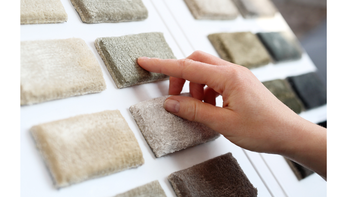 customers hand touching a carpet sample out of a book 